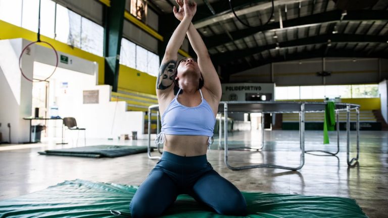 Focused gymnast in a sports hall performing exercises on a mat.